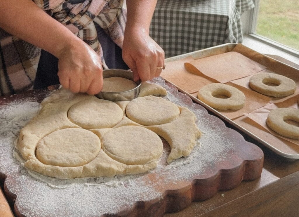 Homemade potato donuts tossed in cinnamon sugar, dough getting cut out to potato donuts