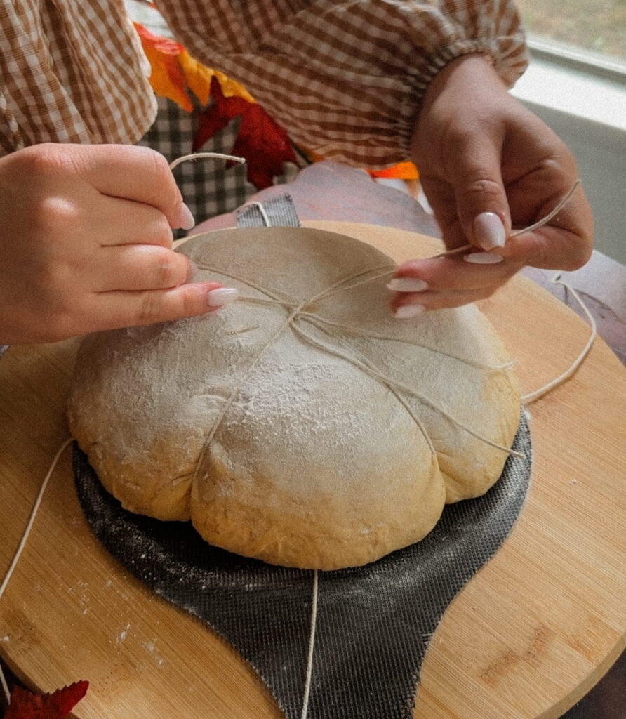 Kitchen twine arranged around pumpkin-shaped sourdough