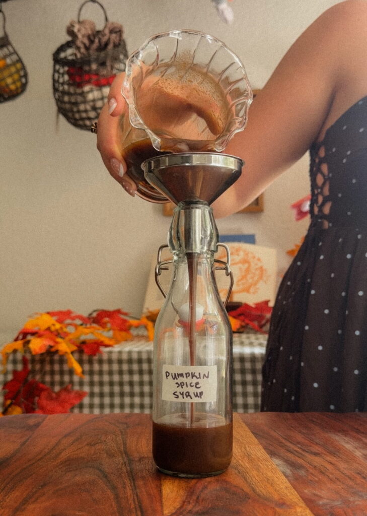 Pumpkin spice syrup being poured into glass bottle